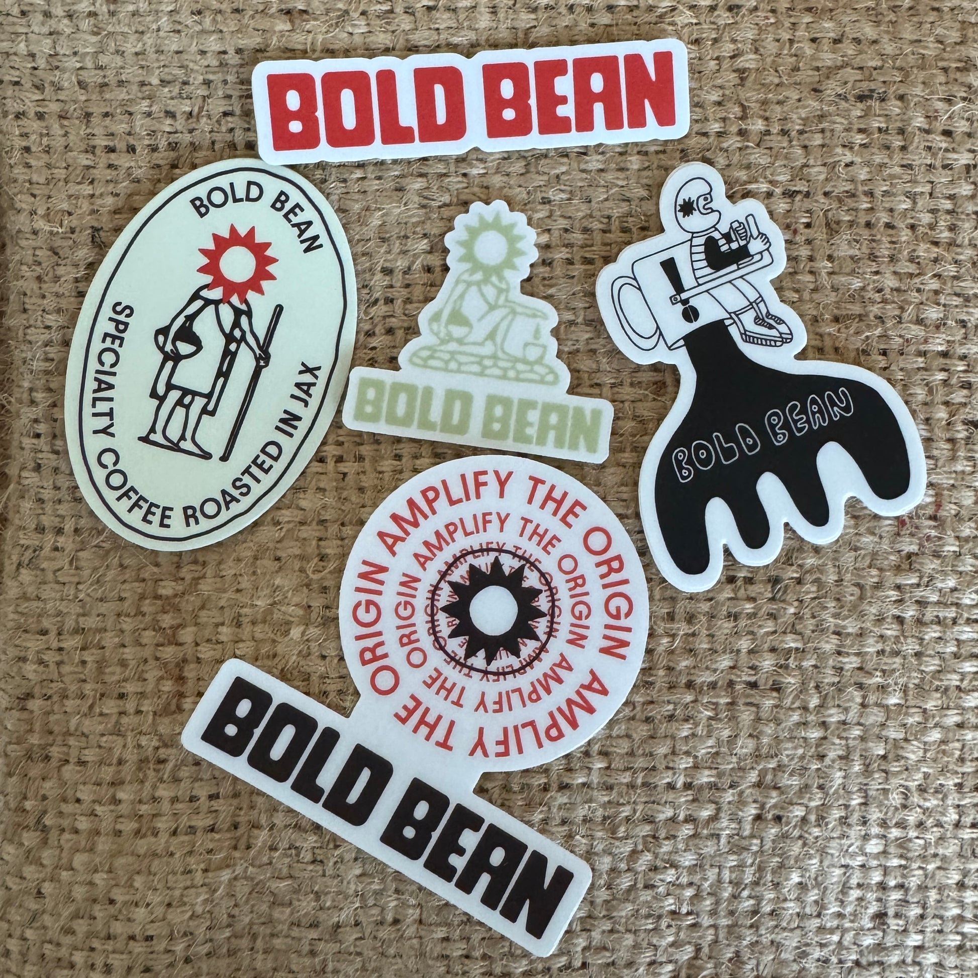 Collection of 'Bold Bean' branded stickers on a textured fabric background